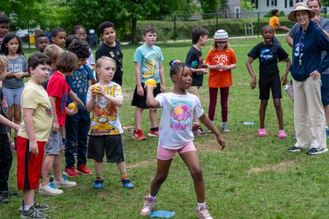 young girl throwing a ball at an outdoor event