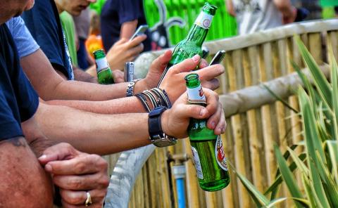 Men holding bottles of beer at an outdoor event