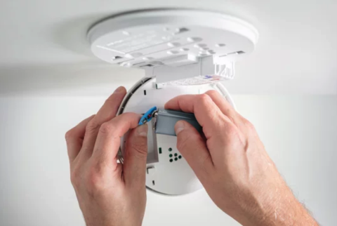 person putting batteries in smoke alarm