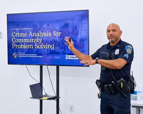 Police officer speaking with TV showing slides