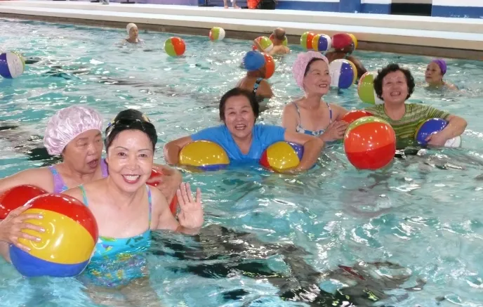 A small group of female senior citizens in an indoor pool with beach balls