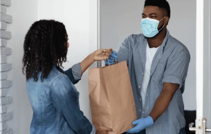 Woman taking brown paper bag from man