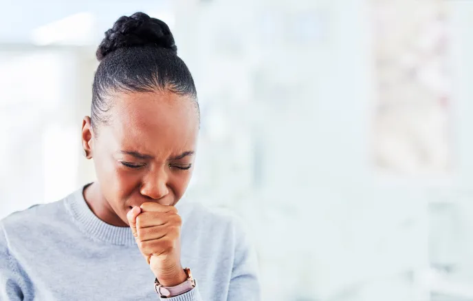 Woman coughing into her hand