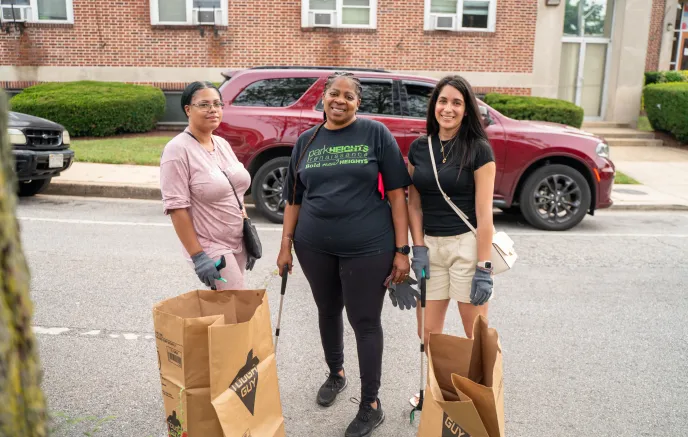 Three women volunteering to clean up the neighborhood