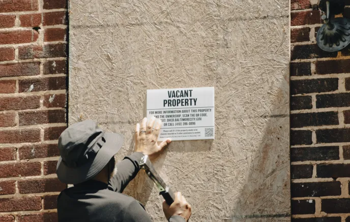 Code Enforcement officer hammering a vacant property sign onto a plywood board