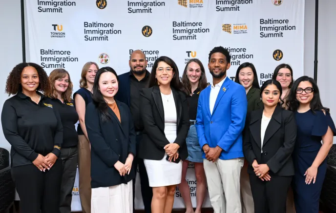 MIMA staff pose with Mayor Brandon M. Scott in front of a patterned backdrop