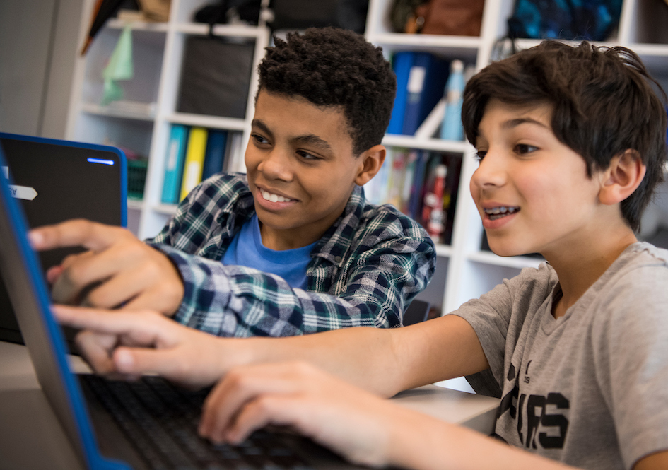 Two students looking at a laptop together in a classroom