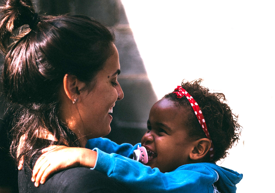 Toddler smiling and hugging teacher