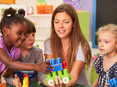 Young children and a teacher at a table with colorful blocks