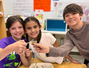 Three students smiling while working