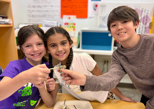 Three students smiling while working