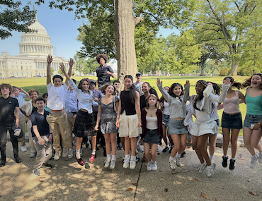 Bank Street eighth grade students jumping on lawn with the Capitol Building behind them