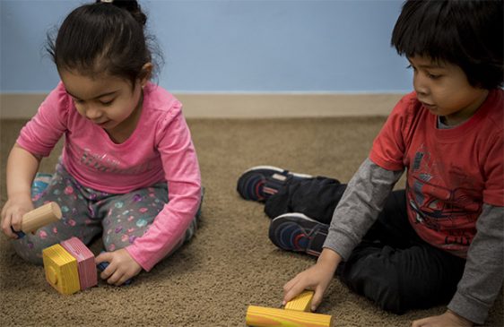 Kids playing with blocks and a wooden hammer