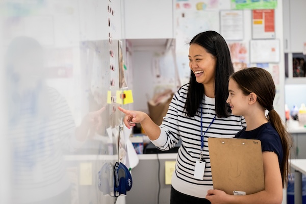 Teacher and student looking at whiteboard smiling