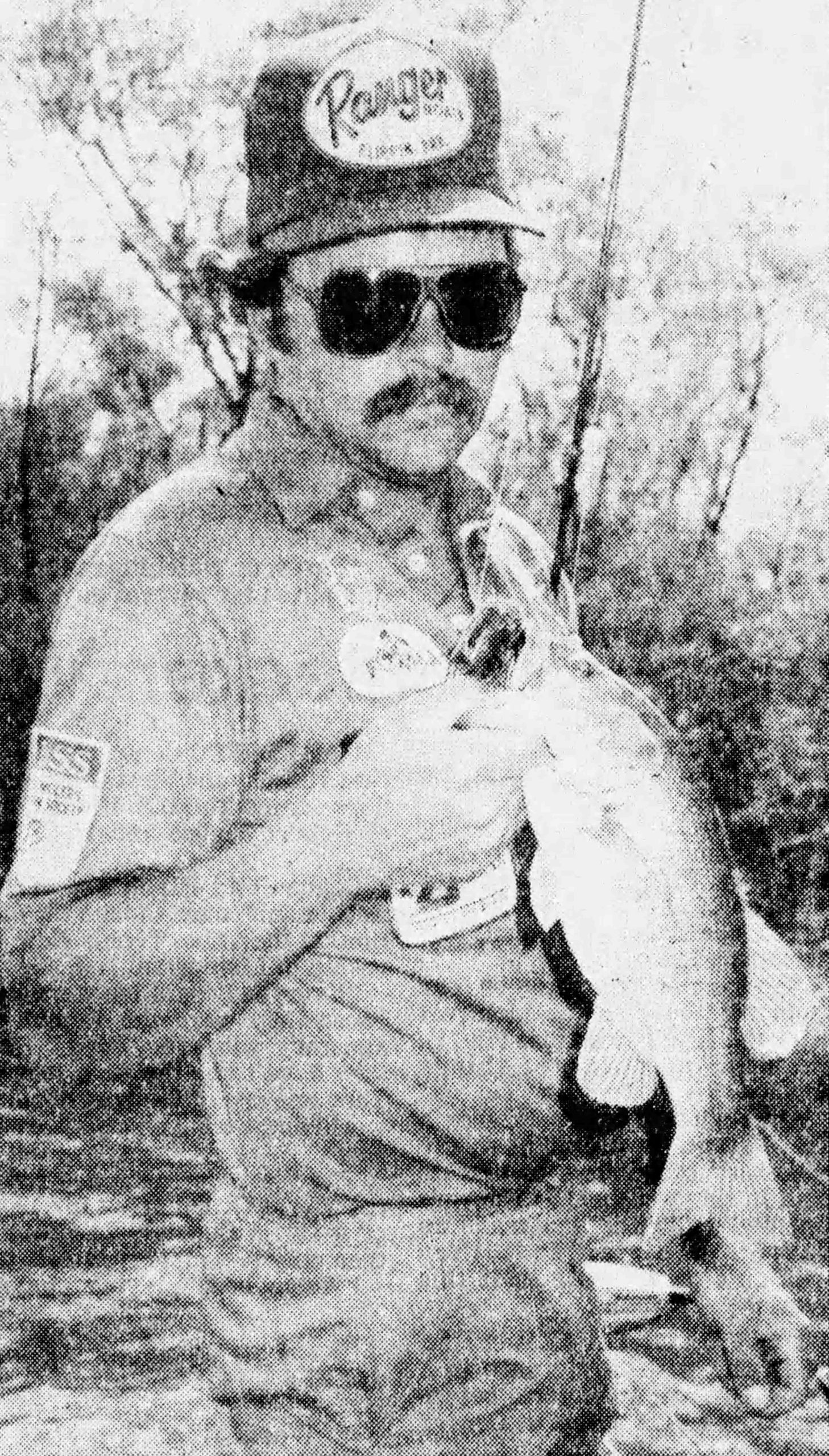 Biffle__Jul__1987 compressed Original Caption: Biffle unhooks a chunky Eufala black bass during last week's fishing outing with the author. Tulsa World, July 1987. World Staff photo