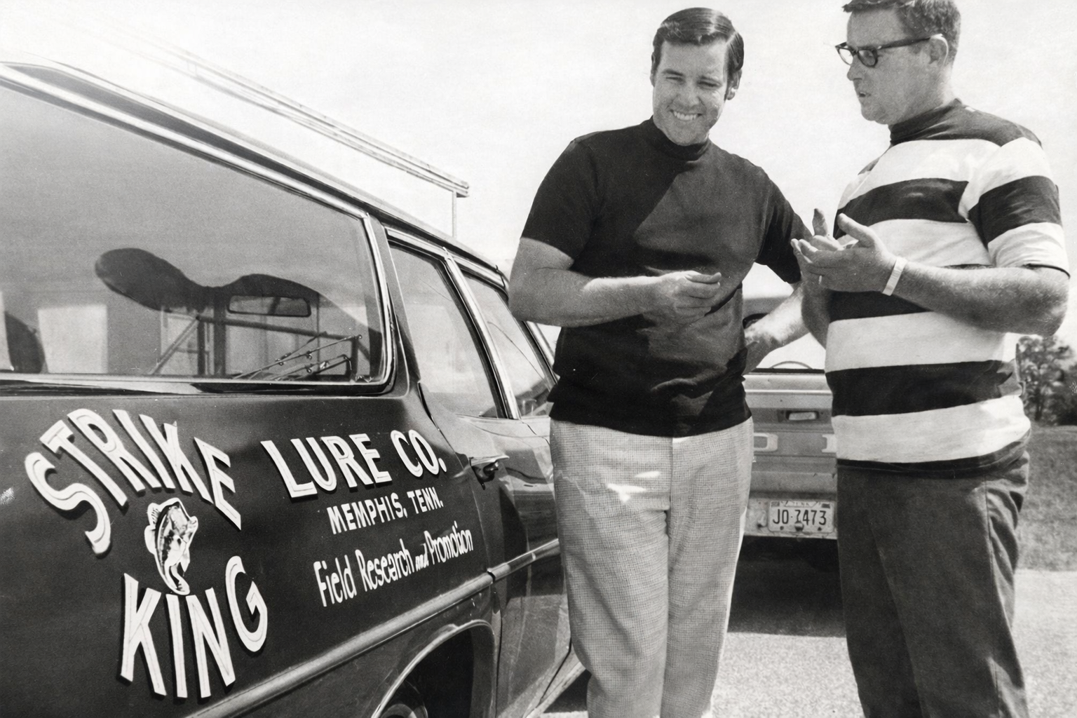 Charles Spence and Bill Dance shortly after purchasing Strike King 1967 Charles Spence and Bill Dance stand next to Bill's tow vehicle emblazoned with the new Strike King Lure Company logo. Image Strike King Lure Company, 1967.