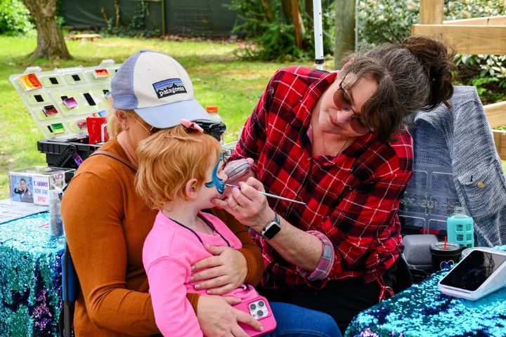 A child is getting her face painted by a Salisbury Zoo volunteer