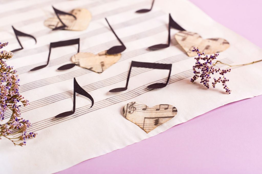 The concept of love for music. Paper notes and hearts on a music sheet.