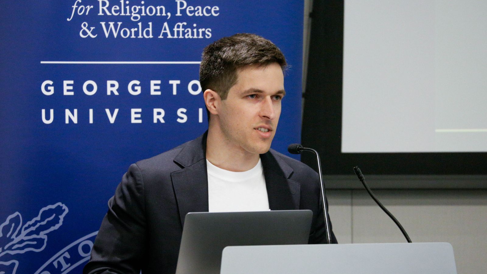 Nick Scrimenti, Director of Student Programs, opens the Hoya Paxa Student Symposium