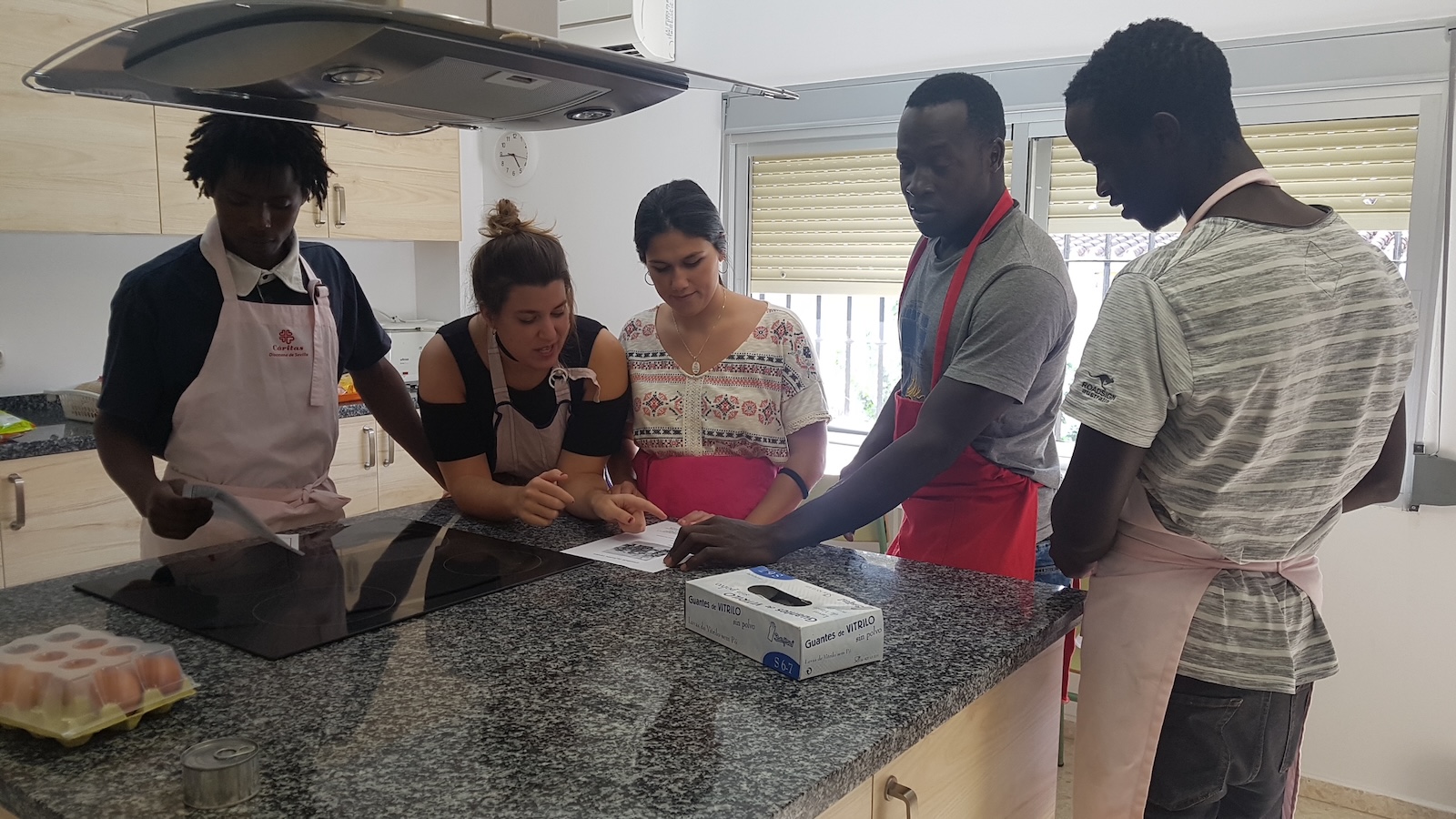 People in a kitchen reading a recipe