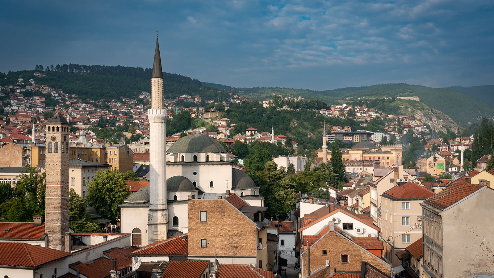 Cityscape of Sarajevo, Bosnia and Herzegovina, with a minaret in the foreground and green hills in the background
