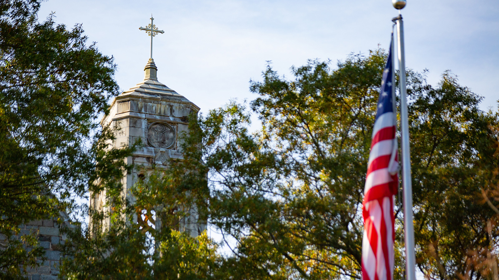 Cross-topped tower of Copley Hall with an American flag in the foreground