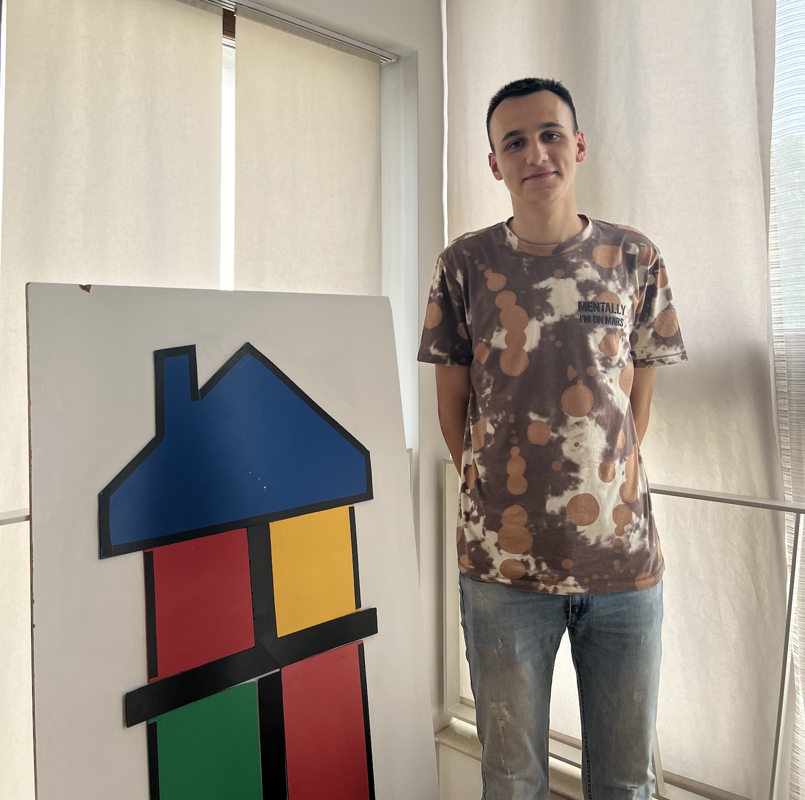 Manuel standing next to a picture of a house