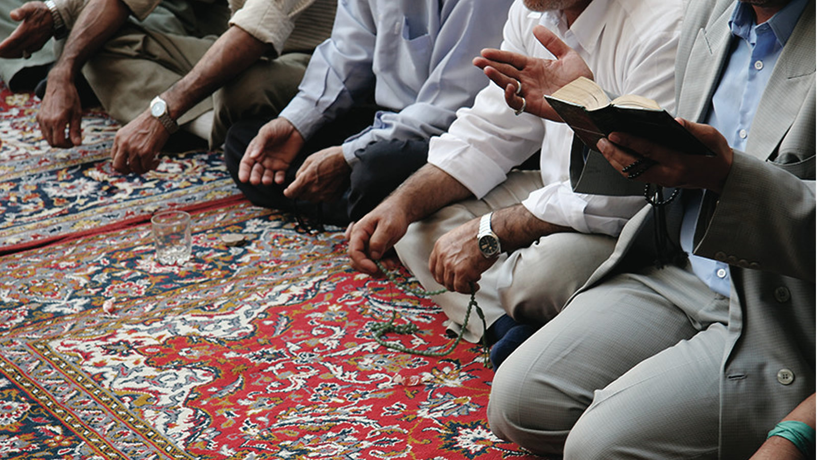 Muslim men gather on a prayer rug