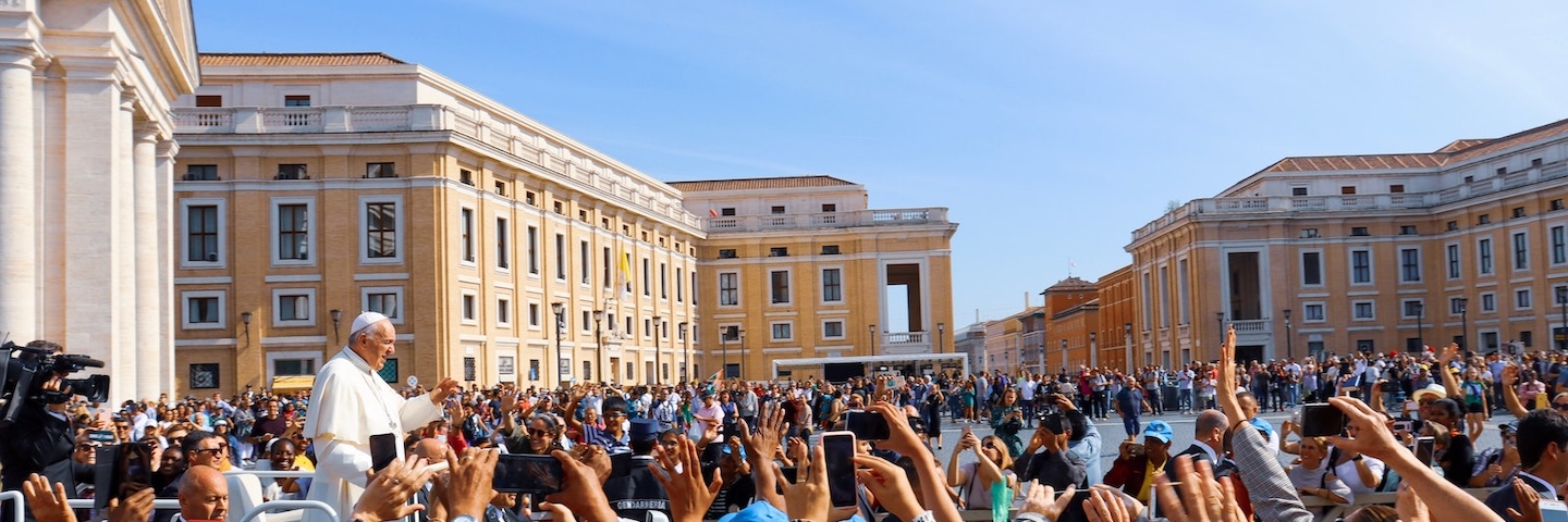 Pope Francis stands in front of a large crowd at the Vatican.