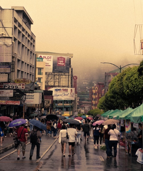 People walking down the street with umbrellas in the Philippines