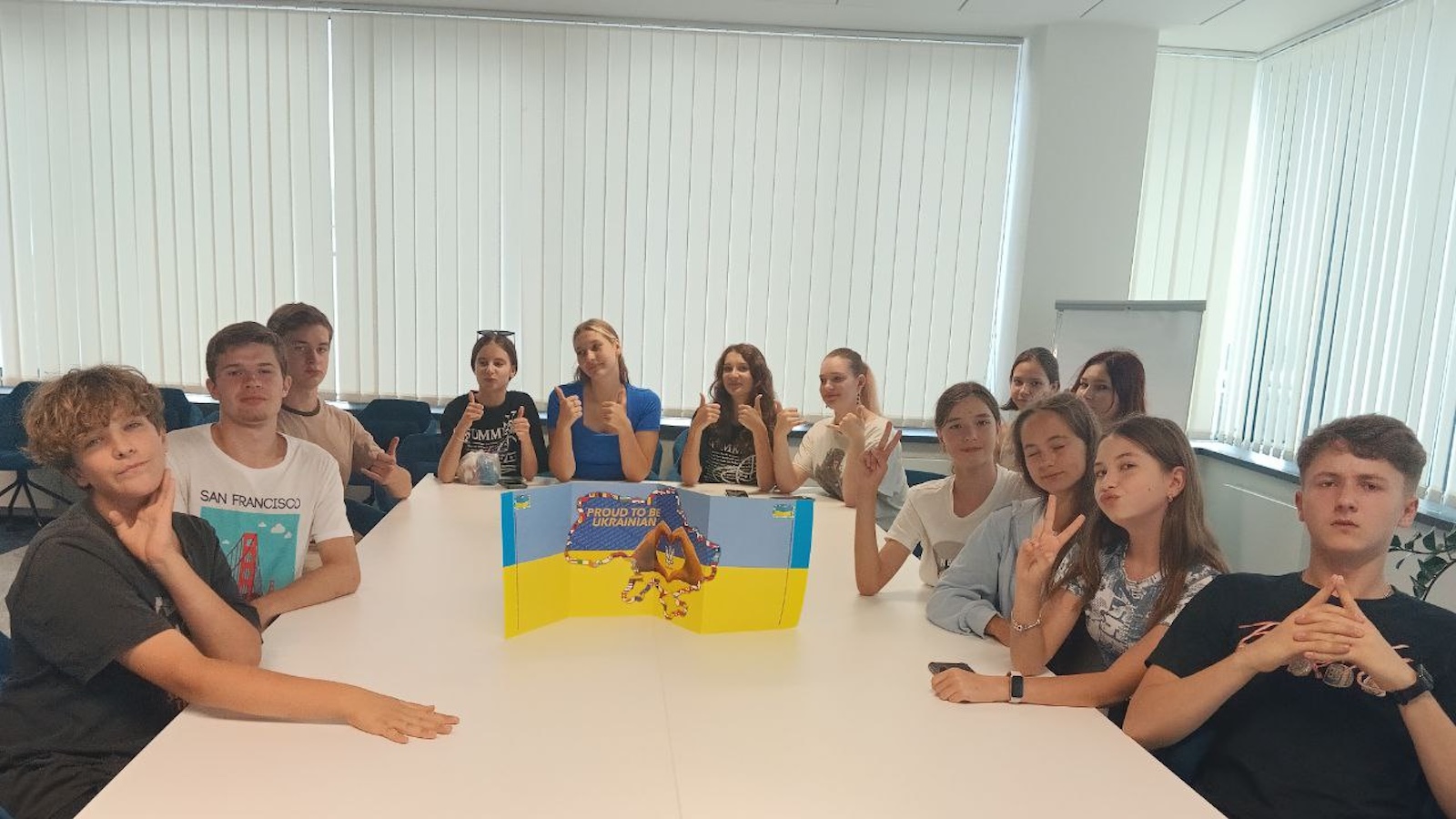 Students surround a Ukrainian flag at a white table