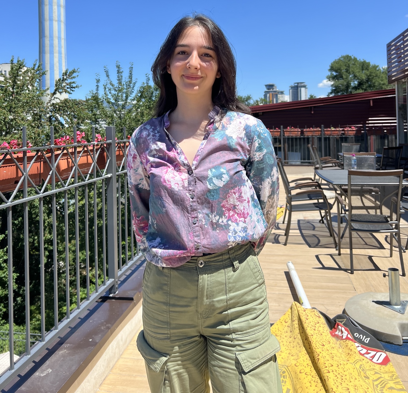 Una stands outside in a floral shirt and green pants