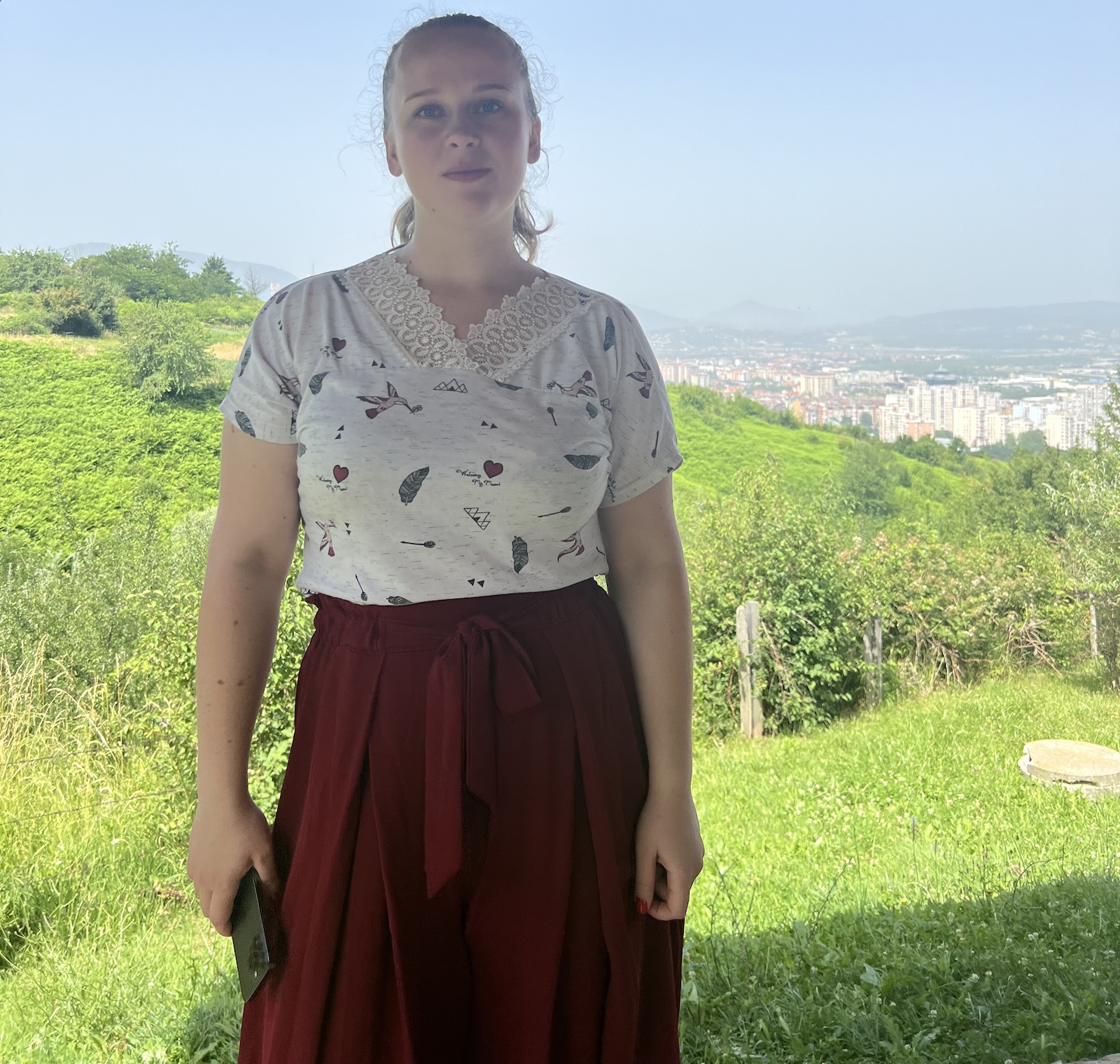 Zaklina Brnadic standing outside in a white top and red skirt