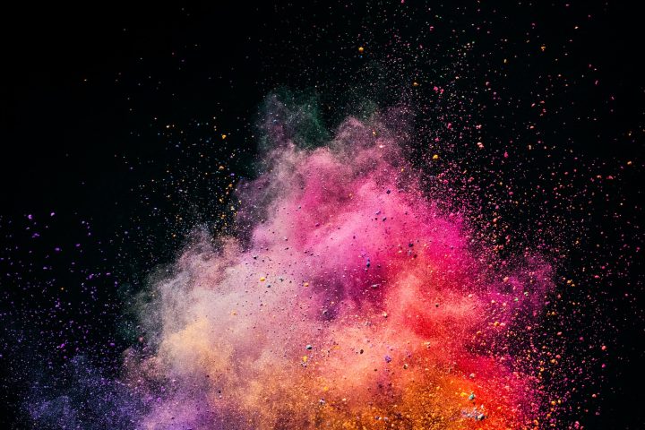 Holi powder exploding on black background.