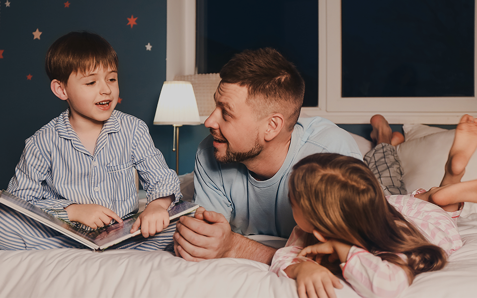 Pais com 2 filhos na cama criando o clima para dormir