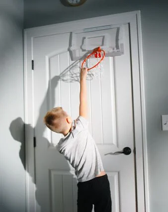 a boy plays youth basketball at home with a portable basketball hoop