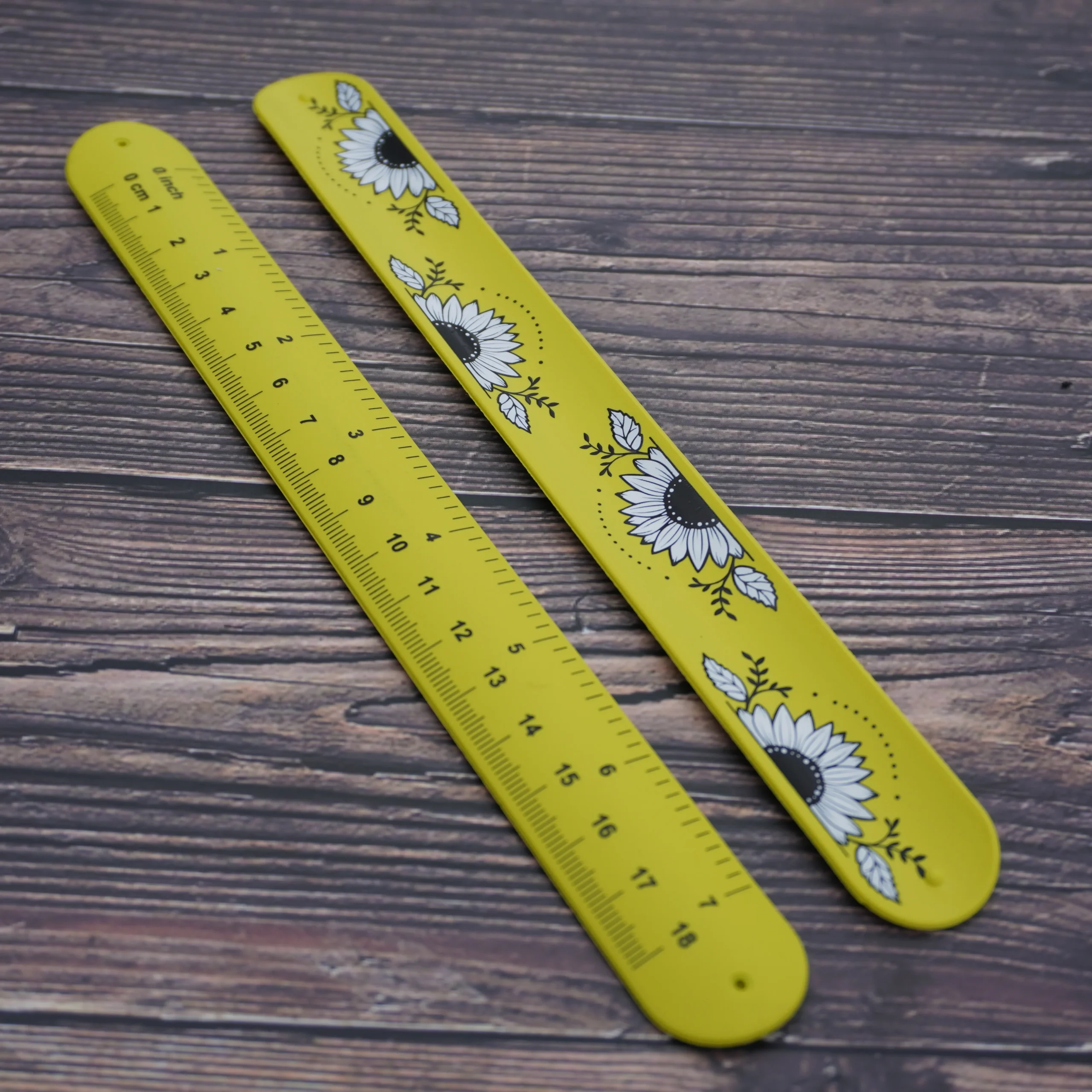 A yellow tape measure bracelet with a graphic design sits on a wooden table.