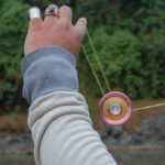 The hand figure of a man playing a yoyo by using basic yoyo tricks for beginners