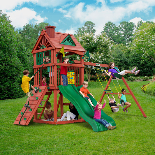 Boys and girls happily played on the cedar swing, wooden climbing ladder, and slide in the backyard. Trees can be seen in the background, with a cloud-like sky as the backdrop.