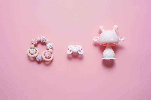 Baby Accessories Concept: Natural Rubber Teether, Caterpillar Toy And Baby Pacifier, Over Pink Background