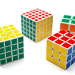 Different versions of the Rubik's Cube, shown isolated on a white background. The Rubik's Cube is a 3D mechanical puzzle that utilizes the PLL Parity 4x4 algorithm to solve the alignment problem.