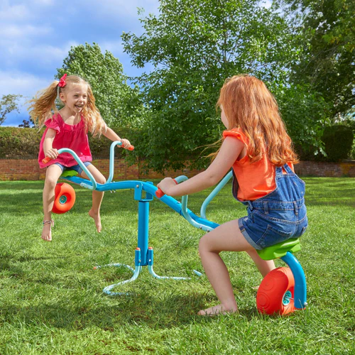 Two little girls playing on steel indoor seesaw in an open area in the garden at home