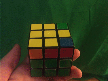 Dynamic yellow Rubik’s Cross solution view, green background, in hand