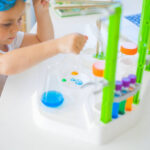 A cute little girl is conducting experiments at home with colored liquids using a Toy Scientist Kit