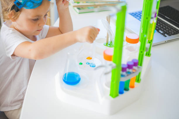 A cute little girl is conducting experiments at home with colored liquids using a Toy Scientist Kit