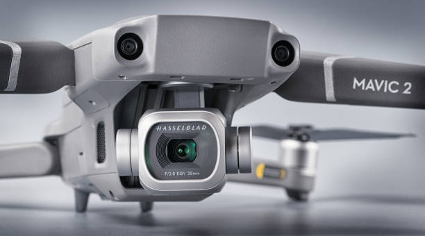 The DJI Mavic 2 Pro drone, equipped with a Hasselblad L1D-20c 12K video camera, is shown with the focus on the camera, and its clarity is compared to that of a 4K video camera drone.