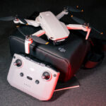 DJI Mavic Mini 2 4K video camera drone, a quadcopter, with remote controller, under red lighting.