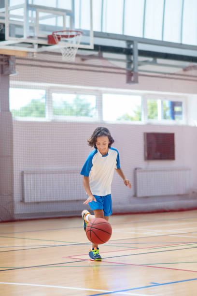 A Teenager Is Practicing Basketball In An Indoor Basketball Court Using Basketball Gifts For 10 Year Old Boy