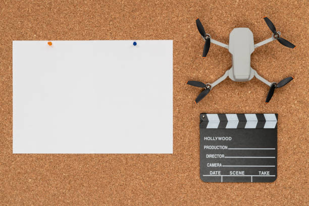 A cork background with a large white sheet of paper, a small drone (Best Drones for Cinematography), and a clapperboard placed on top.