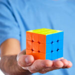 A Man Holding A Solved Rubik's Cube From A Magic Cube Competition